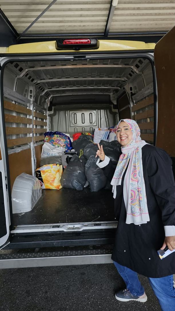 Yara Gamal, Thamarat’s founder, standing beside the open back of a van loaded with bags of donations.